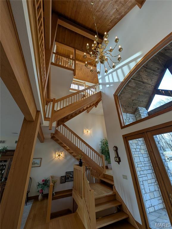 1 River Ridge Rd, Grafton, IL 62037 - staircase featuring a high ceiling, a chandelier, wood ceiling, wood finished floors, and baseboards