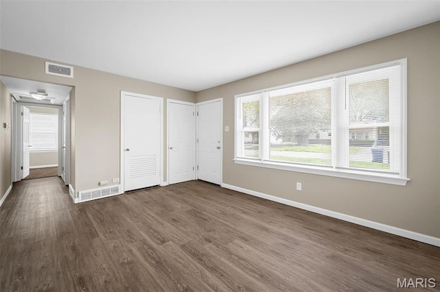 11225 Saint Shawn Ln, Saint Ann, MO 63074 - unfurnished bedroom featuring baseboards, dark wood finished floors, and two closets