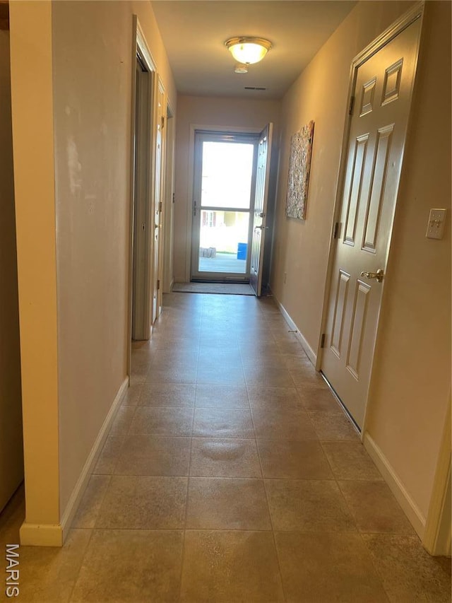 hall featuring baseboards and light tile patterned flooring