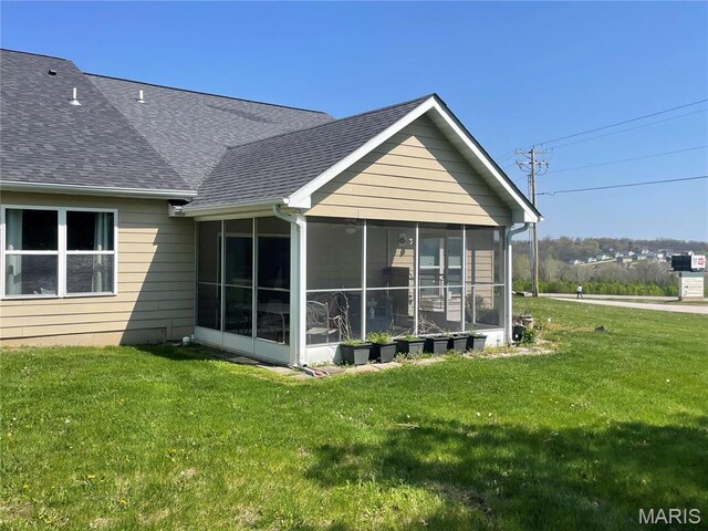 rear view of property featuring a sunroom, roof with shingles, and a yard