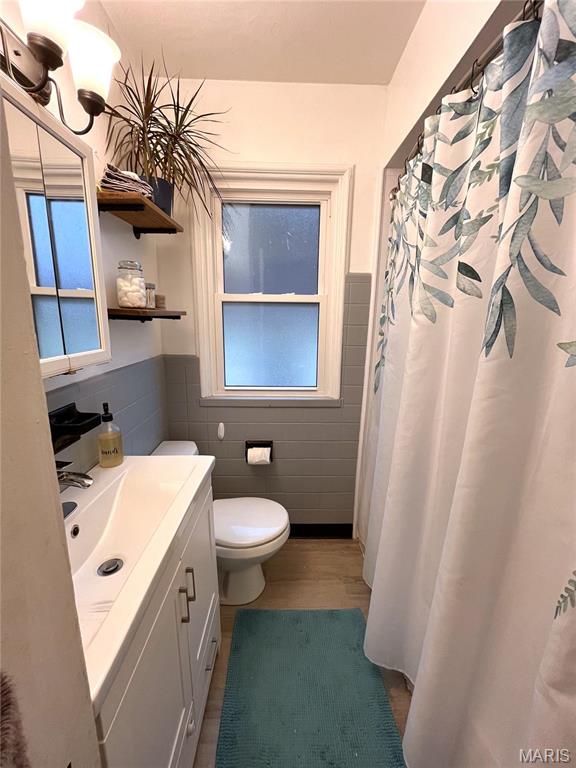 1531 Prather Ave, Saint Louis, MO 63139 - full bathroom with tile walls, toilet, vanity, a wainscoted wall, and plenty of natural light