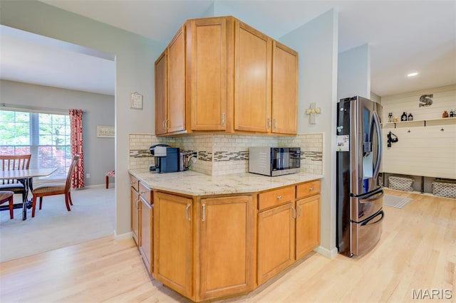 1024 Brook Mont Dr, Ofallon, MO 63366 - kitchen with stainless steel fridge with ice dispenser, black microwave, light wood finished floors, light stone countertops, and tasteful backsplash
