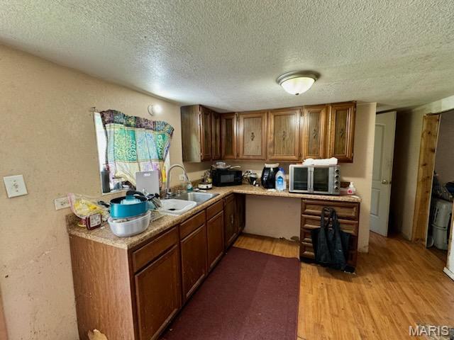 1018 Hayward St, Hannibal, MO 63401 - kitchen with a sink, black microwave, stainless steel microwave, light wood finished floors, and a textured ceiling