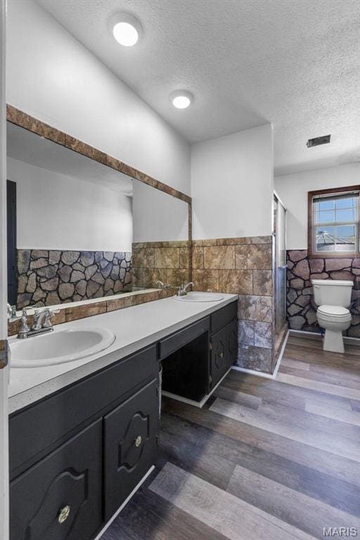 2112 County Highway 264, Gideon, MO 63848 - bathroom with tile walls, a wainscoted wall, toilet, double vanity, and a stall shower