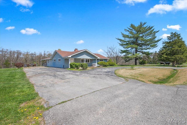 single story home with driveway, a front yard, and a chimney