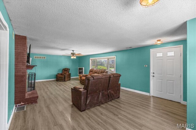 living area with wood finished floors, baseboards, and a textured ceiling