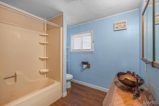 bathroom featuring wood finished floors, toilet, a textured ceiling, ornamental molding, and shower / tub combination