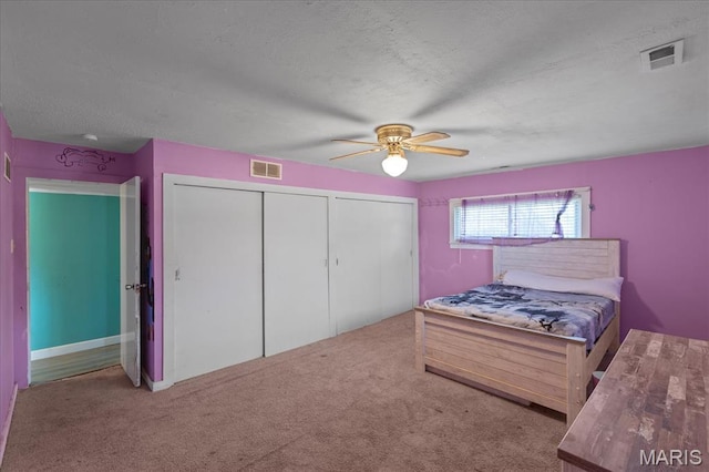 carpeted bedroom with ceiling fan and a textured ceiling