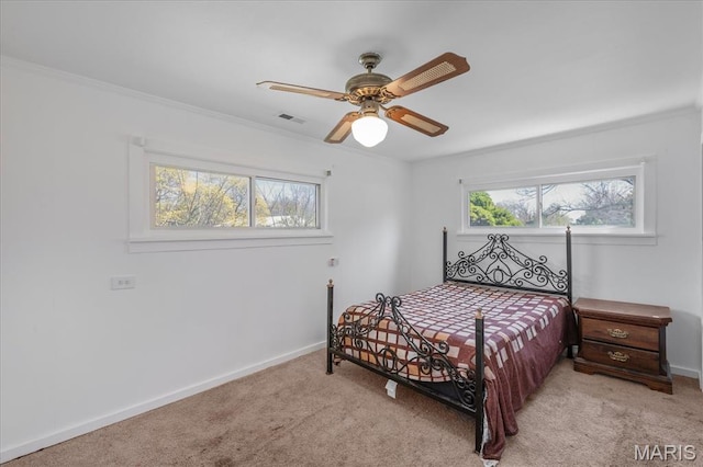 carpeted bedroom featuring baseboards, crown molding, and a ceiling fan