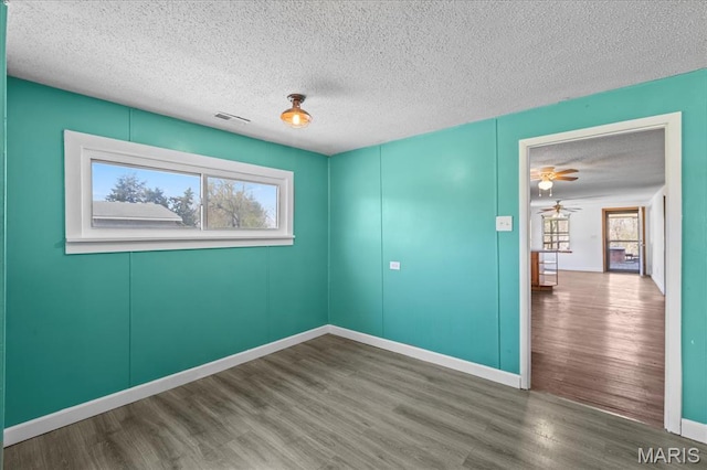 spare room with wood finished floors, a textured ceiling, ceiling fan, and baseboards
