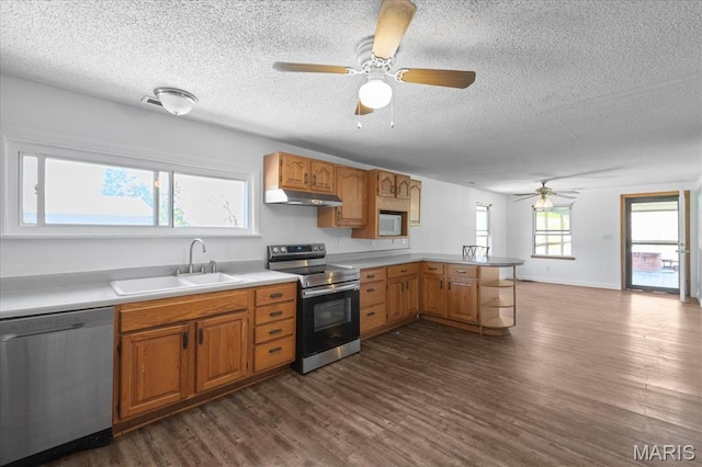 kitchen featuring stainless steel appliances, a sink, ceiling fan, a textured ceiling, and a peninsula
