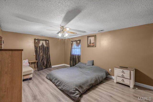 bedroom with light wood-type flooring, ceiling fan, baseboards, and a textured ceiling