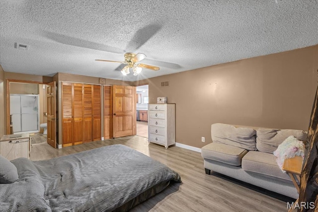bedroom with baseboards, a closet, light wood finished floors, a ceiling fan, and a textured ceiling