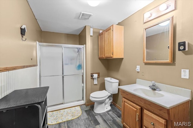 bathroom with wood finished floors, a shower stall, toilet, and vanity