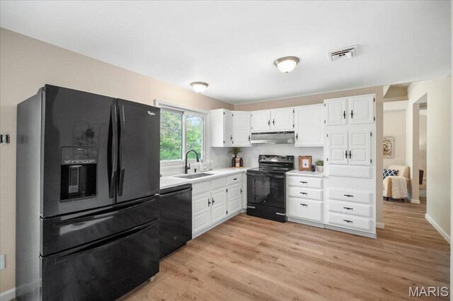 3105 Newgate Dr, Florissant, MO 63033 - kitchen featuring black appliances, under cabinet range hood, a sink, white cabinets, and light wood-style flooring