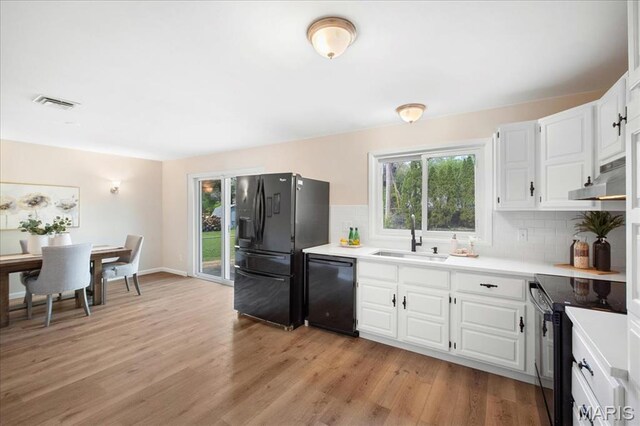 3105 Newgate Dr, Florissant, MO 63033 - kitchen featuring a sink, black appliances, under cabinet range hood, tasteful backsplash, and light wood finished floors
