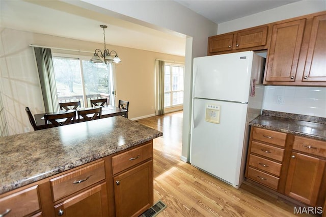 1167 Appleseed Ln Unit D, Olivette, MO 63132 - kitchen featuring freestanding refrigerator, light wood finished floors, brown cabinets, a chandelier, and hanging light fixtures