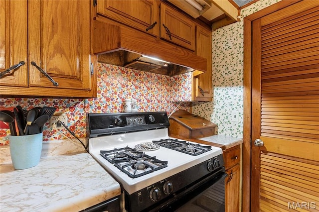 1821 Pcr 916, Perryville, MO 63775 - kitchen featuring gas range, wallpapered walls, light countertops, brown cabinetry, and extractor fan