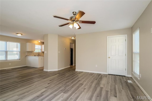 4007 Lafayette Ave, Saint Louis, MO 63110 - unfurnished living room with wood finished floors, ceiling fan, baseboards, and a sink