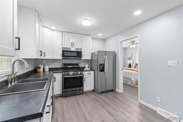 449 Hillcrest Blvd, Ballwin, MO 63021 - kitchen featuring stainless steel appliances, a sink, dark countertops, white cabinetry, and tasteful backsplash