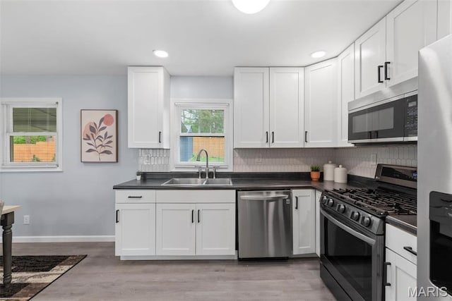 449 Hillcrest Blvd, Ballwin, MO 63021 - kitchen featuring stainless steel appliances, a sink, dark countertops, tasteful backsplash, and white cabinets