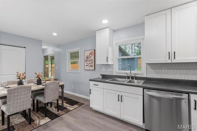 449 Hillcrest Blvd, Ballwin, MO 63021 - kitchen with stainless steel dishwasher, a sink, dark countertops, white cabinets, and decorative backsplash