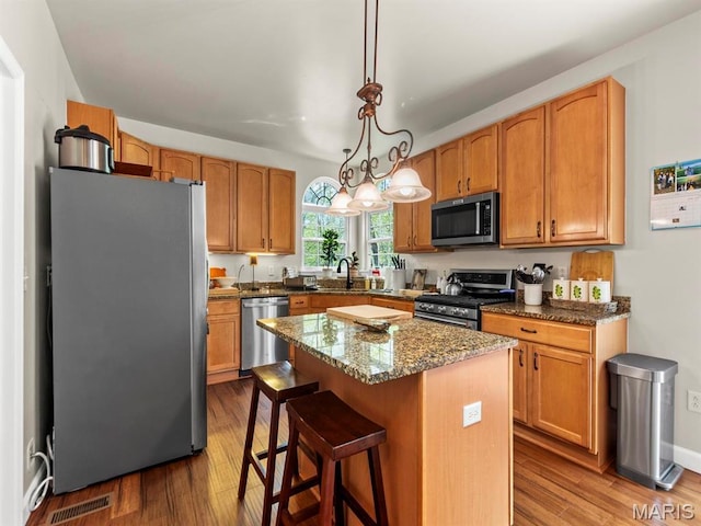 1509 Cedar Ridge Dr, Ofallon, IL 62269 - kitchen with stainless steel appliances, a sink, a kitchen island, wood finished floors, and decorative light fixtures