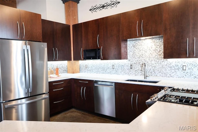 1015 Washington Ave Unit 507, Saint Louis, MO 63101 - kitchen featuring appliances with stainless steel finishes, a sink, backsplash, dark brown cabinetry, and light stone counters