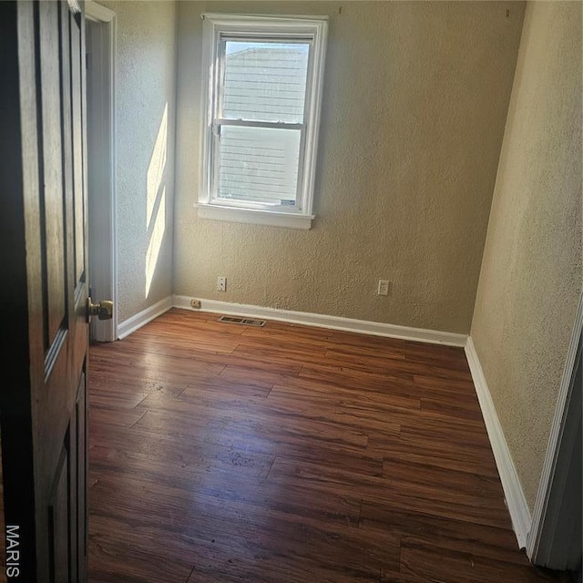 600 Plum, Cahokia, IL 62206 - unfurnished room featuring dark wood-style flooring, a textured wall, and baseboards