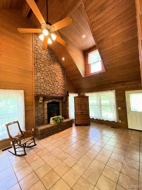 unfurnished living room featuring high vaulted ceiling, wooden ceiling, wood walls, light tile patterned floors, and a ceiling fan