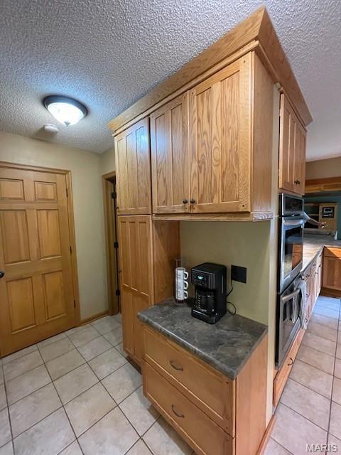 577 Schluersburg Rd, Augusta, MO 63332 - kitchen with a textured ceiling, light tile patterned floors, brown cabinets, and dark countertops