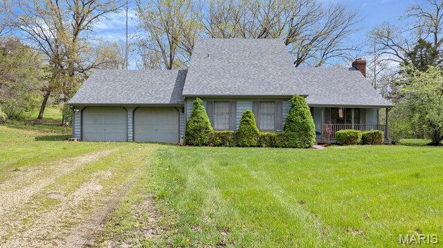 28470 Sunnyside Rd, Warrenton, MO 63383 - view of front facade featuring dirt driveway, a chimney, a front lawn, and an attached garage