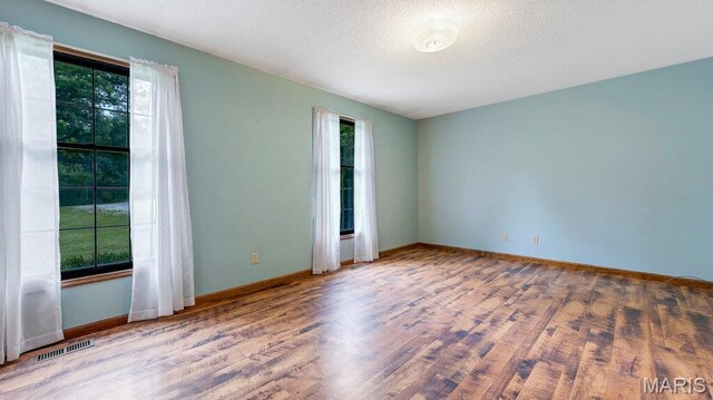 28470 Sunnyside Rd, Warrenton, MO 63383 - unfurnished room with plenty of natural light, wood finished floors, baseboards, and a textured ceiling