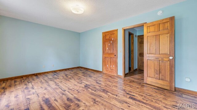 28470 Sunnyside Rd, Warrenton, MO 63383 - unfurnished bedroom with wood finished floors, baseboards, and a textured ceiling