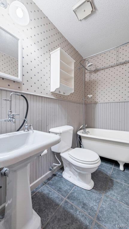28470 Sunnyside Rd, Warrenton, MO 63383 - full bath with wallpapered walls, a wainscoted wall, toilet, shower / bath combination, and tile patterned flooring