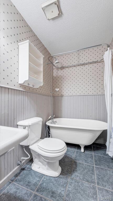 28470 Sunnyside Rd, Warrenton, MO 63383 - bathroom featuring wainscoting, a freestanding bath, wallpapered walls, toilet, and a shower with shower curtain