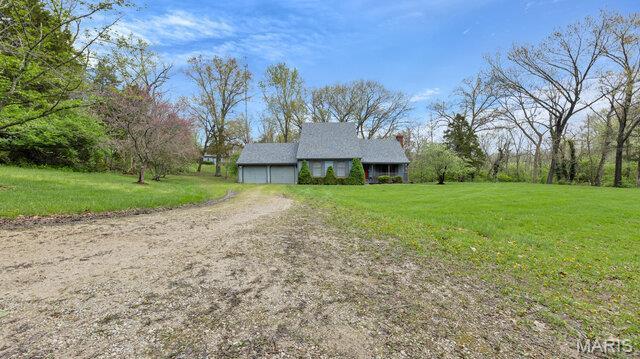 28470 Sunnyside Rd, Warrenton, MO 63383 - view of front facade featuring a front lawn, dirt driveway, and an attached garage