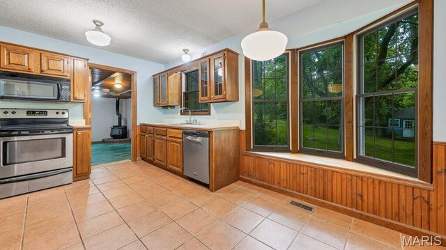 28470 Sunnyside Rd, Warrenton, MO 63383 - kitchen with stainless steel appliances, a wood stove, a sink, brown cabinets, and light countertops