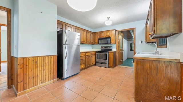 28470 Sunnyside Rd, Warrenton, MO 63383 - kitchen featuring stainless steel appliances, a sink, brown cabinetry, a wainscoted wall, and light countertops