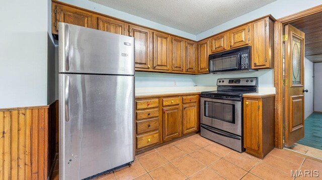 28470 Sunnyside Rd, Warrenton, MO 63383 - kitchen with stainless steel appliances, brown cabinets, light countertops, light tile patterned flooring, and a textured ceiling