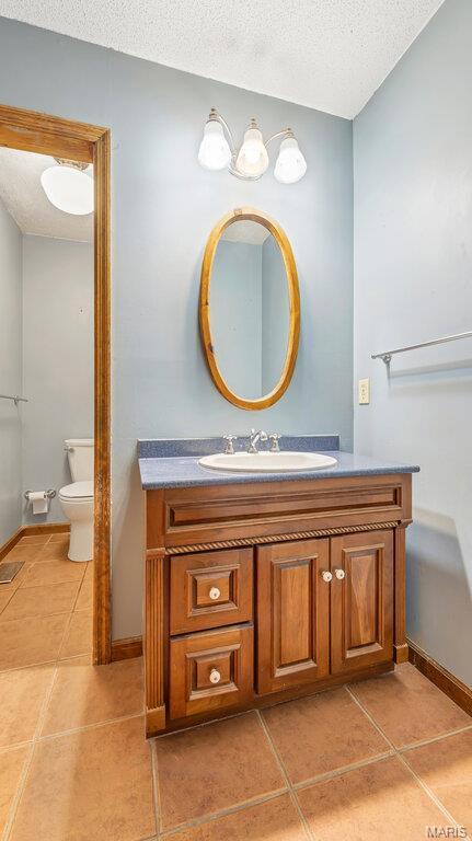 28470 Sunnyside Rd, Warrenton, MO 63383 - bathroom with tile patterned floors, vanity, toilet, a textured ceiling, and baseboards