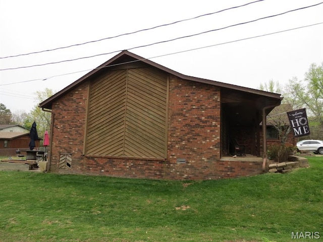 view of side of home featuring a lawn and brick siding