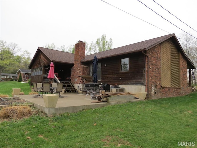 rear view of house with a patio area, a chimney, a yard, and brick siding