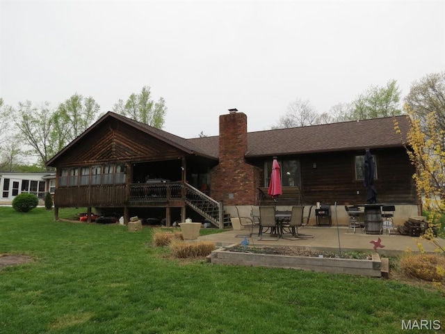 back of house featuring a chimney, a patio area, a lawn, stairs, and a shingled roof