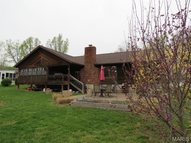 rear view of property featuring a chimney, a lawn, roof with shingles, a patio, and stairway