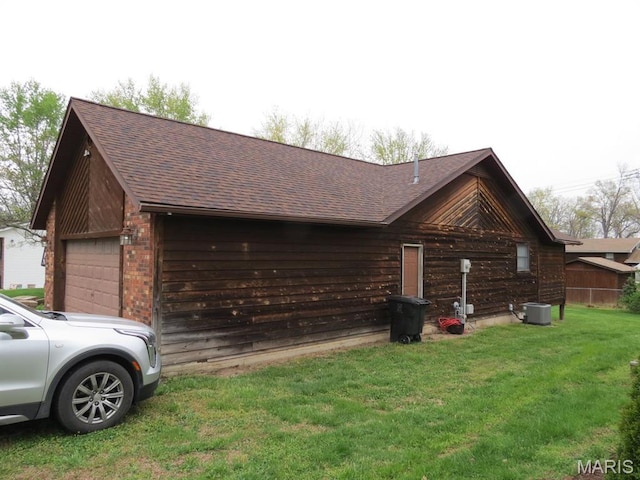 view of side of property featuring brick siding, roof with shingles, a yard, and central AC
