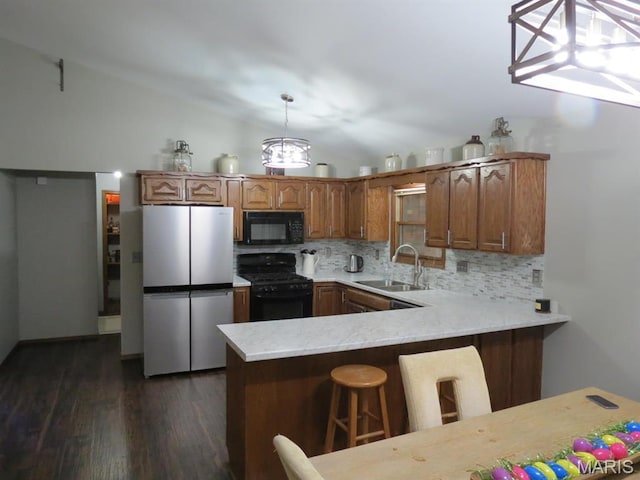 kitchen with black appliances, a sink, lofted ceiling, a peninsula, and backsplash