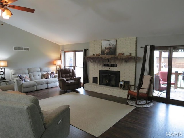 living room featuring wood finished floors, vaulted ceiling, a fireplace, and a ceiling fan