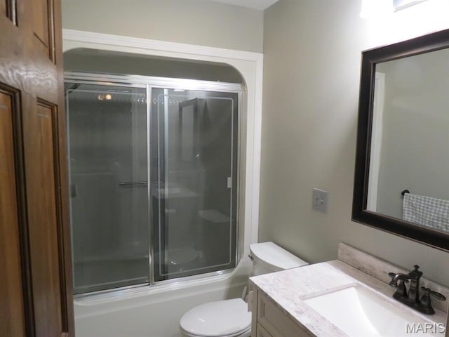 bathroom with toilet, vanity, and combined bath / shower with glass door