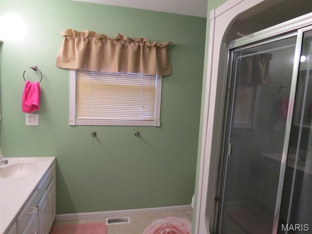 bathroom with tile patterned flooring, baseboards, a stall shower, and vanity